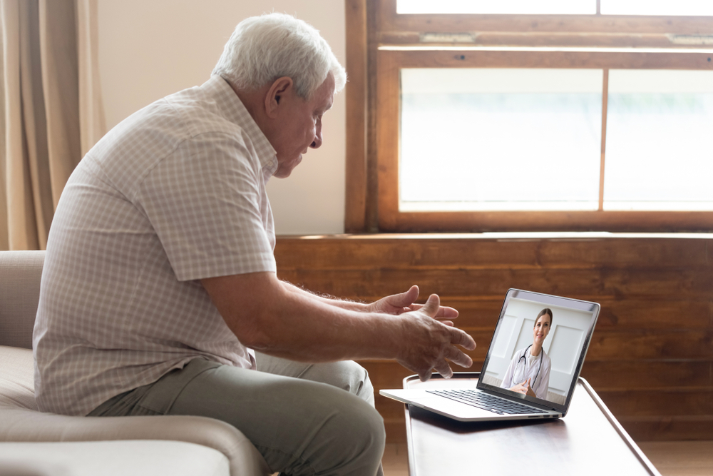 telemedicine for senior citizens. elderly male on sofa during telehealth appointment with naturopathic doctor