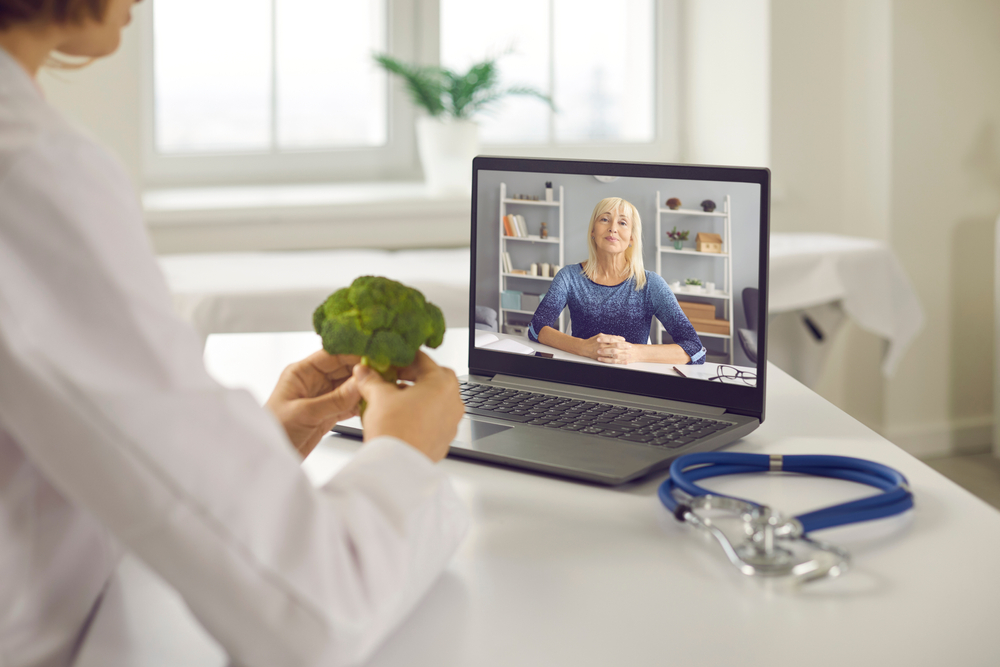 naturopathic doctor showing patient broccoli during online doctor visit to promote wellness